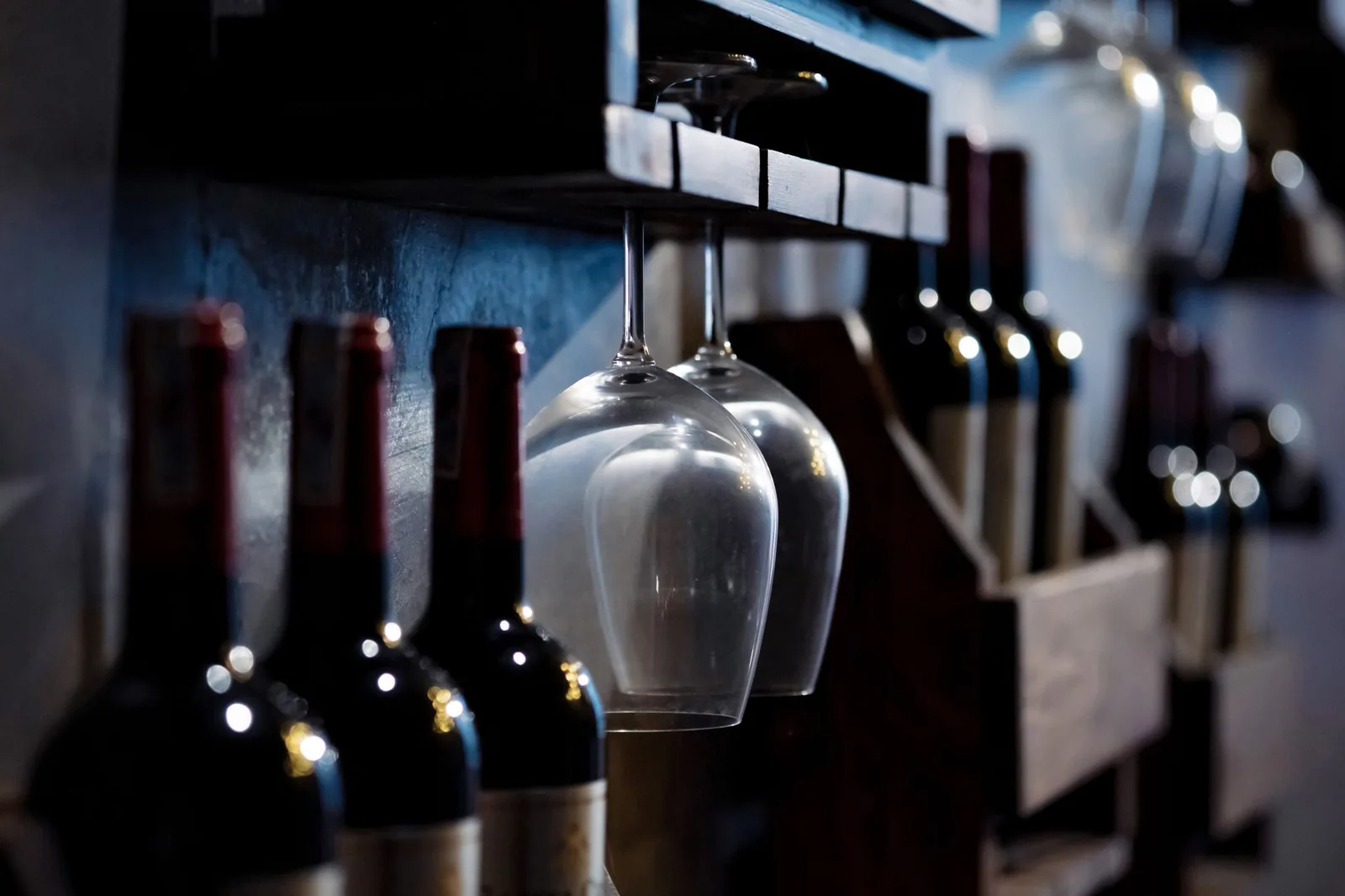 Wine bottles resting on wooden shelves in a dimly lit cellar
