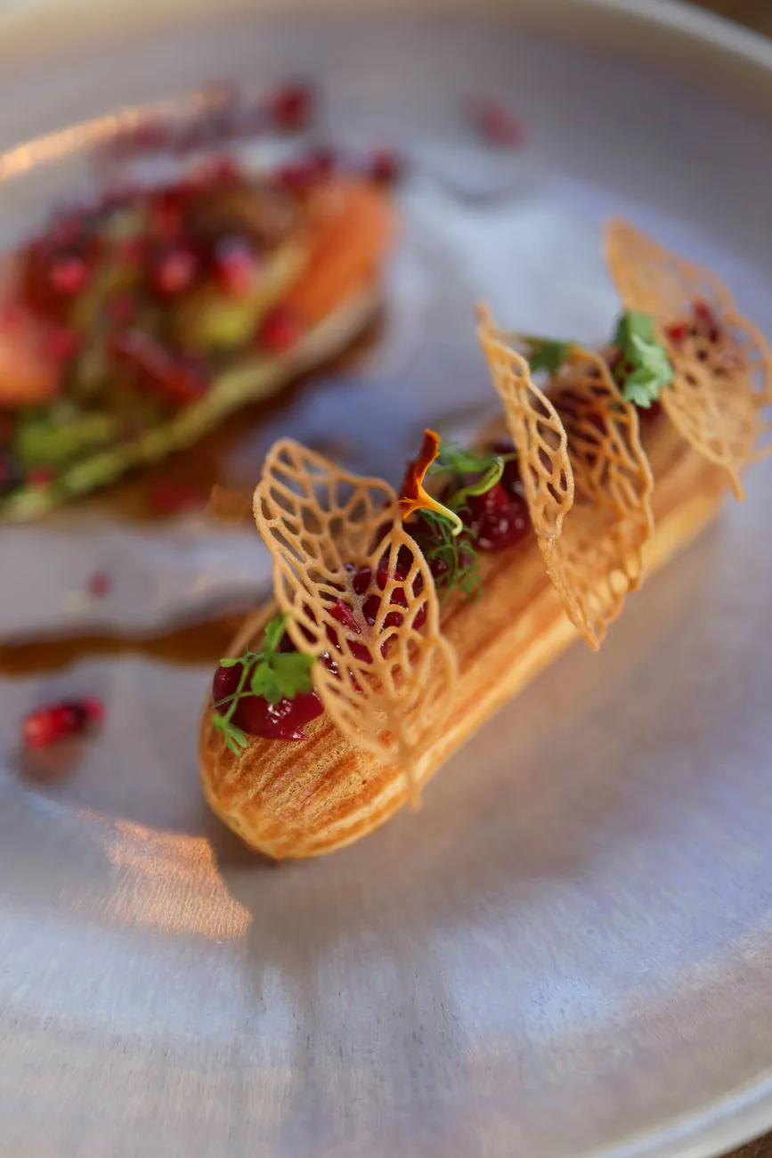 Elegant eclair topped with pomegranate and delicate decorations