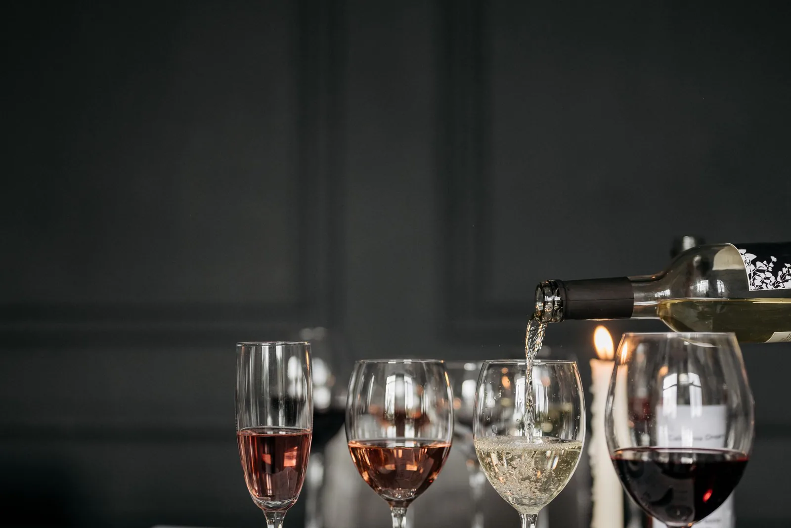 Three glasses of red, white, and rosé wine on a candlelit table